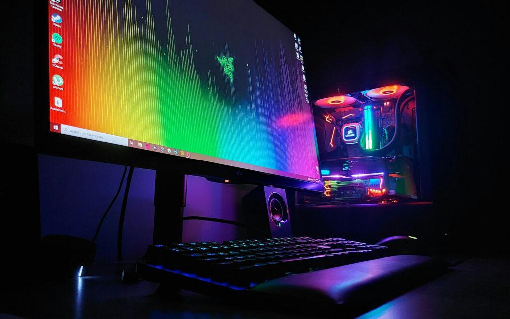 Postazione da gaming con monitor acceso, tastiera retroilluminata e PC con luci colorate