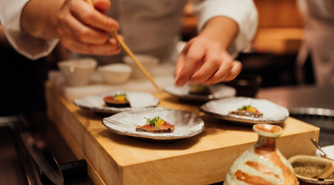 Chef che impiatta con le bacchette al bancone di un ristorante giapponese