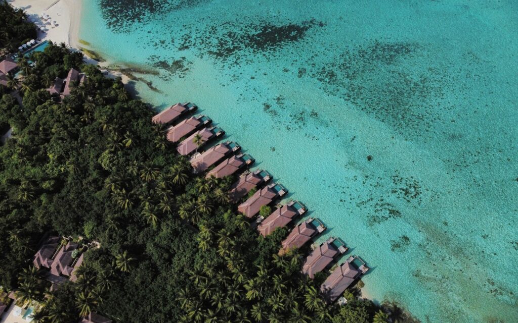 Isola tropicale vista dall'alto con resort, palme e acqua cristallina
