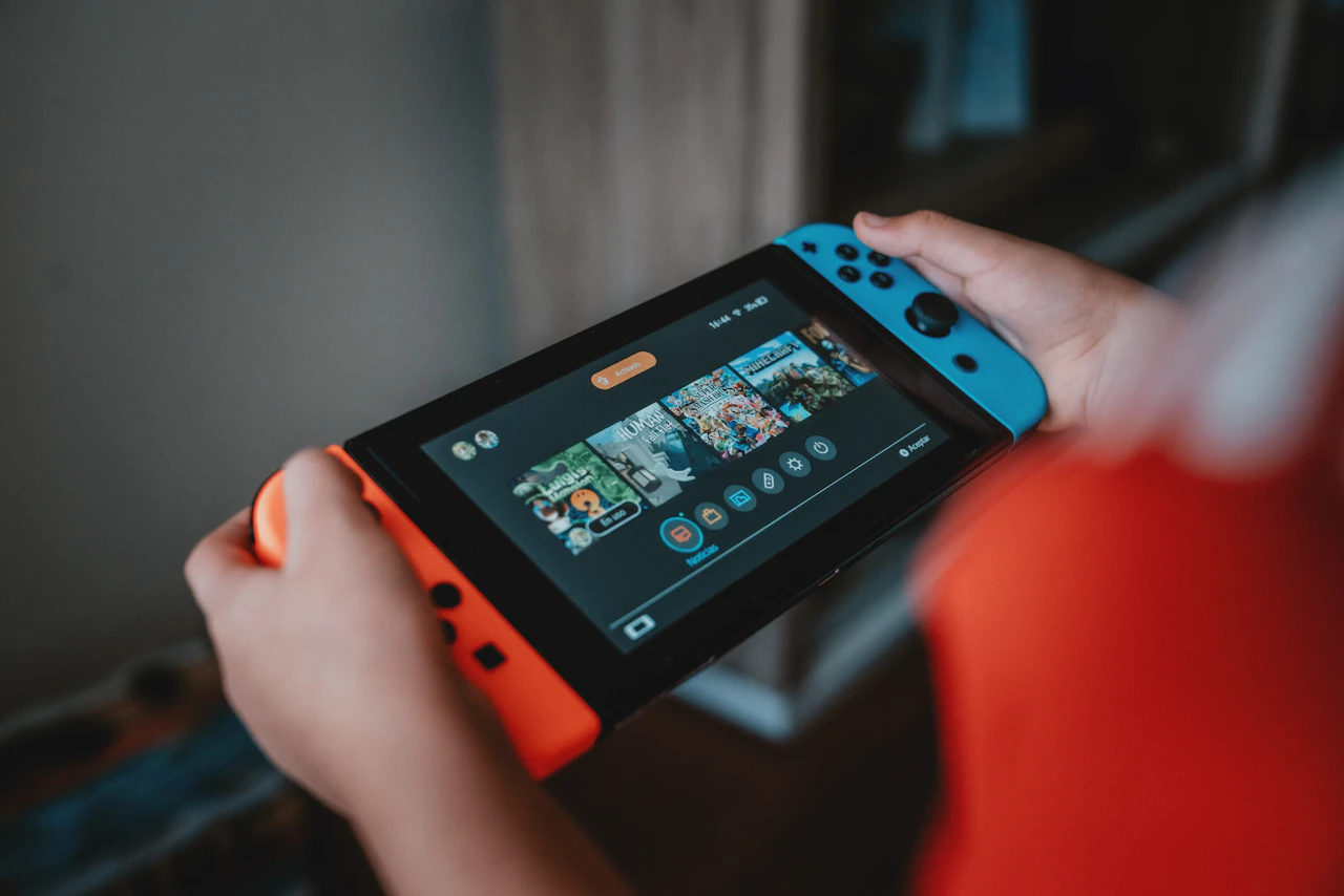 mani che tengono una console Nintendo in modalità portatile